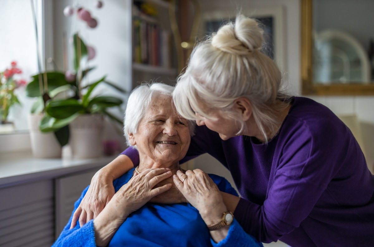 An adult daughter sitting close with her mother at home